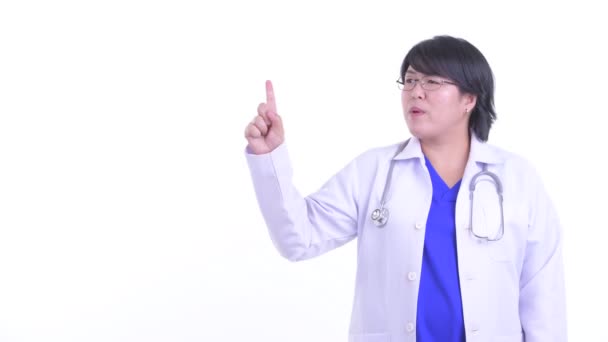 Stressed overweight Asian woman doctor talking while pointing up — Stock Video