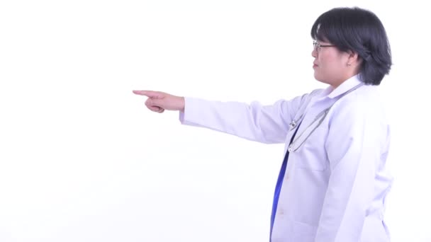 Vue du profil de femme asiatique heureuse en surpoids médecin pointant du doigt — Video