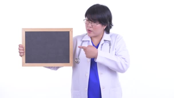 Χαρούμενος υπέρβαρων Ασιάτης/ισσα γυναίκα γιατρός κρατώντας μαυροπίνακα και δίνοντας αντίχειρες επάνω — Αρχείο Βίντεο
