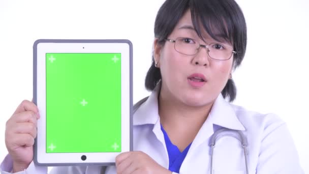 Dijital tablet gösterirken mutlu kilolu Asyalı kadın doktor konuşurken yüzü