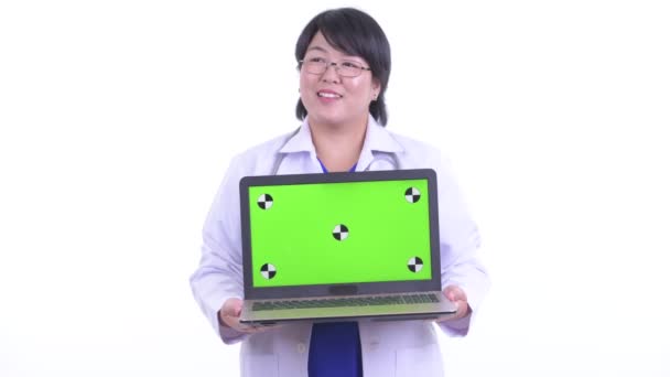 Felice in sovrappeso asiatico donna medico pensando mentre mostrando laptop — Video Stock