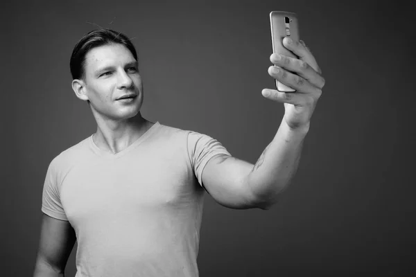 Студийный снимок мускулистого человека, делающего селфи с телефоном — стоковое фото