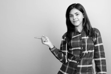 Gri arka plan üzerinde kontrol gömlek giyen genç güzel Hintli kadın