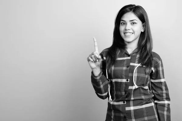 Молодая красивая индийская женщина в клетчатой рубашке на сером фоне — стоковое фото