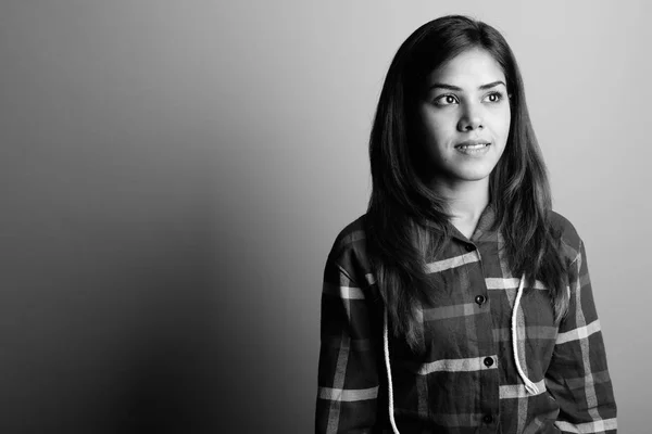 Молодая красивая индийская женщина в клетчатой рубашке на сером фоне — стоковое фото