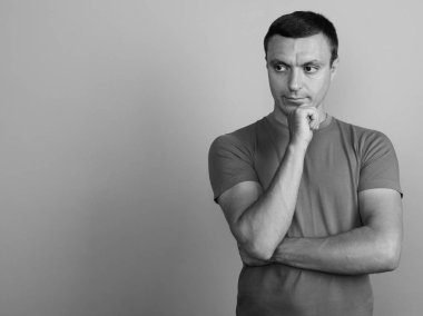 Siyah beyaz çekilen gri arka plan karşı t-shirt giyen adam