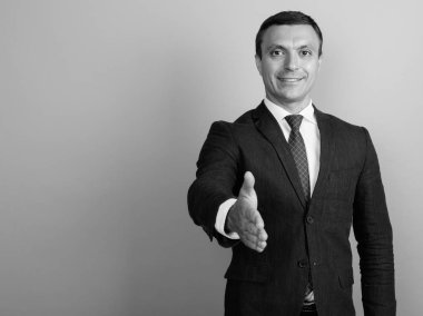 Siyah beyaz çekilen gri arka plan aleyhine takım elbise giyen işadamı