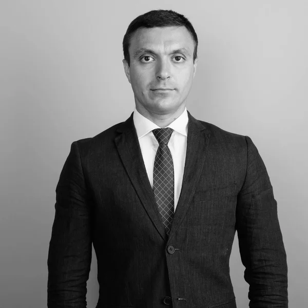 Empresário vestindo terno contra fundo cinza tiro em preto e branco — Fotografia de Stock