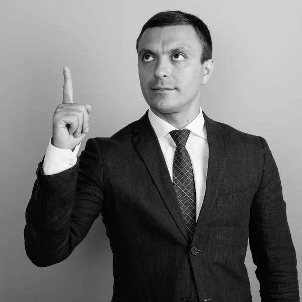 Hombre de negocios con traje contra fondo gris tiro en blanco y negro —  Fotos de Stock