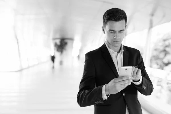 Jonge knappe zakenman met behulp van mobiele telefoon buitenshuis — Stockfoto