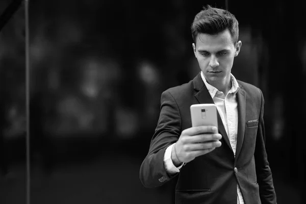 Jeune homme d'affaires beau utilisant le téléphone mobile à l'extérieur — Photo