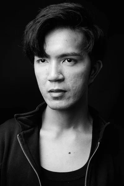 Молодой красивый азиат думает на черном фоне — стоковое фото