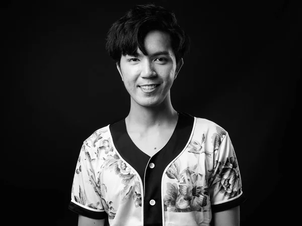 Mladý pohledný asijský muž s úsměvem na černém pozadí — Stock fotografie