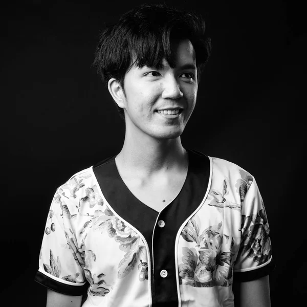 Joven guapo asiático hombre sonriendo sobre negro fondo —  Fotos de Stock