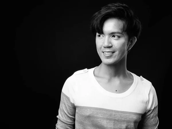 Joven guapo asiático hombre sonriendo sobre negro fondo —  Fotos de Stock
