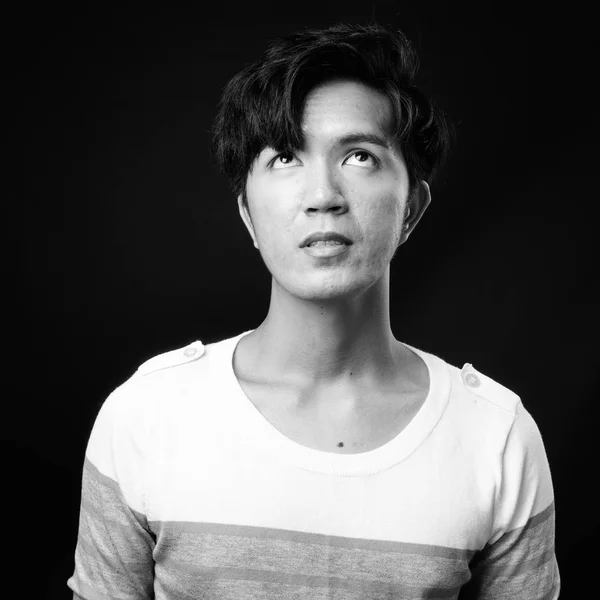 Joven guapo asiático hombre pensando en negro fondo —  Fotos de Stock