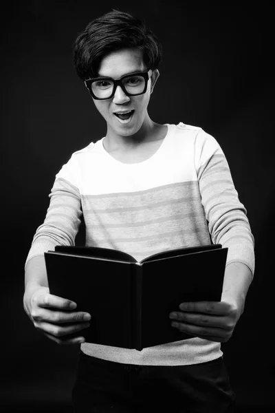 Fiatal csinos ázsiai ember Holding naplója fekete háttér előtt — Stock Fotó