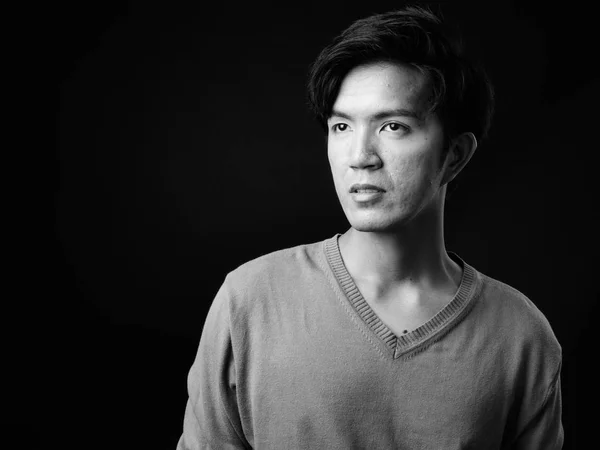 Junger hübscher asiatischer Mann denkt vor schwarzem Hintergrund — Stockfoto