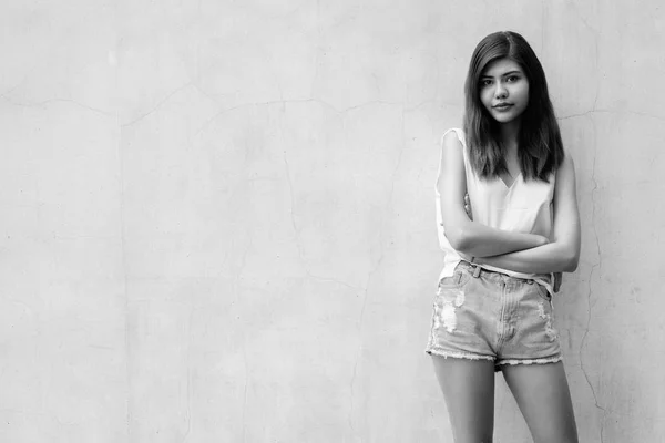 Gyönyörű tinédzser lány szürke fal háttérben a szabadban forgatott fekete-fehér — Stock Fotó