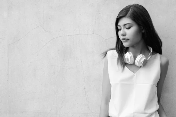 Όμορφη έφηβος κορίτσι με τα ακουστικά κατά γκρι τοίχο φόντο σε εξωτερικούς χώρους shot σε μαύρο και άσπρο — Φωτογραφία Αρχείου
