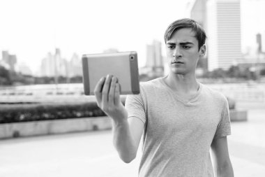 Parkta dinlenirken dijital tablet kullanan genç yakışıklı adam