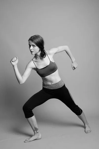 Young beautiful woman ready for gym against gray background — Stock Photo, Image