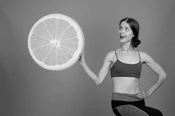 Young beautiful woman ready for gym against gray background — Stock Photo, Image