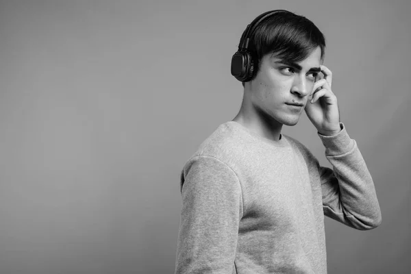 Jovem bonito homem ouvindo música e pronto para ginásio contra fundo cinza — Fotografia de Stock