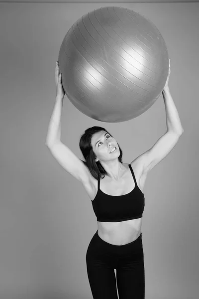 Mladá krásná žena připravena na tělocvičnu proti šedému pozadí — Stock fotografie