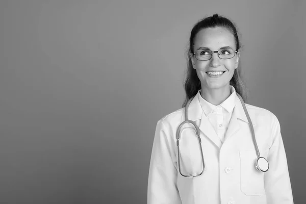 Joven hermosa mujer médico contra fondo gris — Foto de Stock