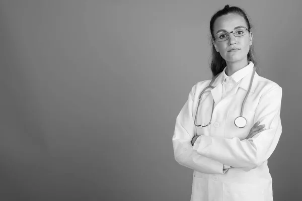 Joven hermosa mujer médico contra fondo gris —  Fotos de Stock