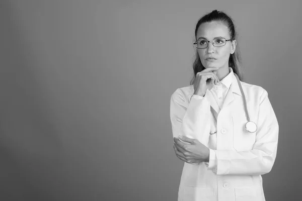 회색 배경에 반대하는 젊고 아름다운 여자 의사 — 스톡 사진