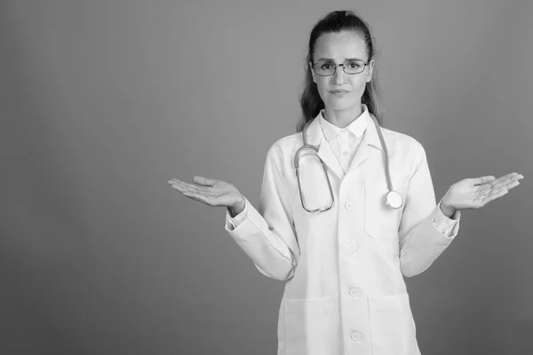 Joven hermosa mujer médico contra fondo gris —  Fotos de Stock