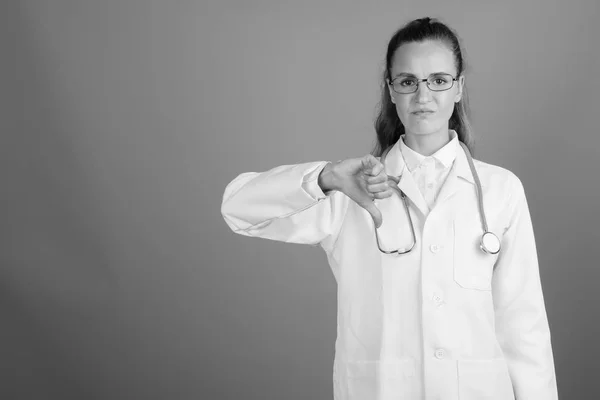 Joven hermosa mujer médico contra fondo gris —  Fotos de Stock