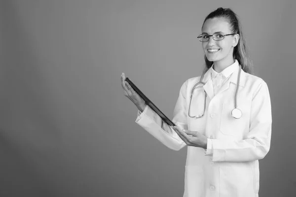 Joven hermosa mujer médico contra fondo gris — Foto de Stock