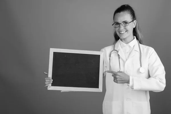 Jovem mulher bonita médico segurando vazio placa preta com espaço de cópia — Fotografia de Stock