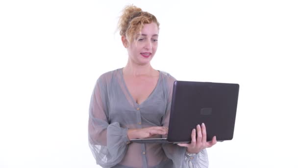 Feliz hermosa mujer rubia hablando mientras se utiliza el ordenador portátil — Vídeo de stock