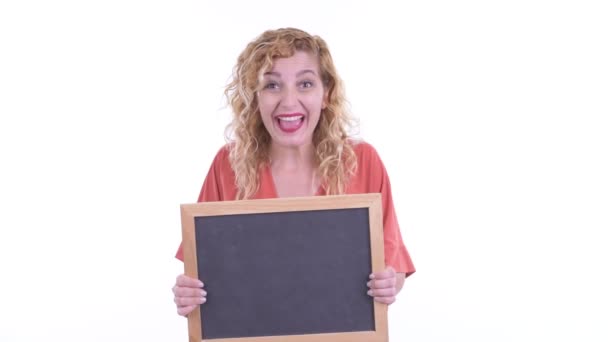 Happy beautiful blonde businesswoman holding blackboard and looking surprised — Stock Video