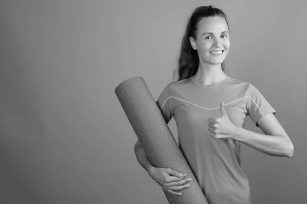 Молодая красивая женщина держит коврик для тренировки йоги — стоковое фото