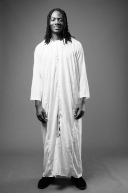 Genç yakışıklı Afrika adam kahverengi zemin karşı geleneksel kıyafetlerle stüdyo çekim