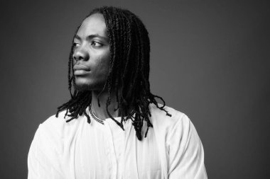 Genç yakışıklı Afrika adam kahverengi zemin karşı geleneksel kıyafetlerle stüdyo çekim