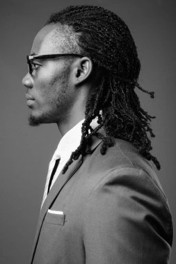 Genç yakışıklı Afrika işadamı kahverengi zemin karşı gözlük ile mavi takım elbise Studio vurdu