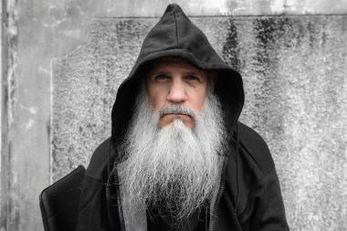 Portrait of mature bald man with long gray beard against grunge concrete wall outdoors