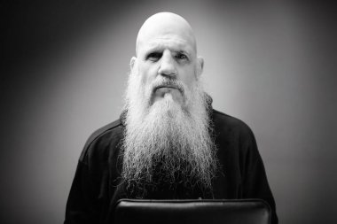 Siyah beyaz dramatik çekimleri olan kel sakallı bir adamın portresi.