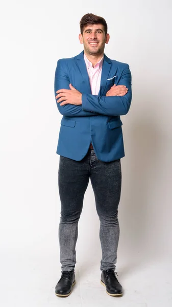 Full body shot of happy young Persian businessman in suit smiling with arms crossed — Stock Photo, Image