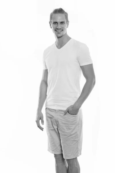 Studio shot of happy young handsome man smiling while standing with hand on pocket — Stock Photo, Image