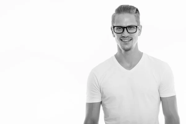 Estudio de tiro de feliz joven guapo hombre sonriendo mientras llevaba gafas — Foto de Stock