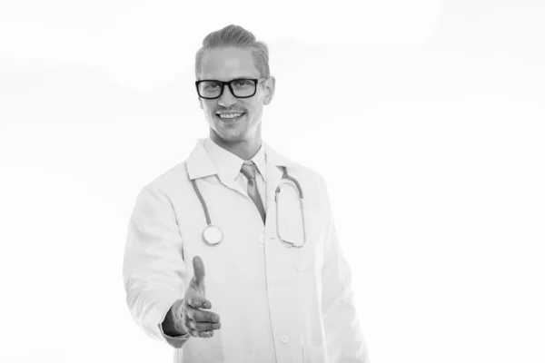 Estúdio tiro de jovem médico homem feliz sorrindo enquanto dá aperto de mão — Fotografia de Stock