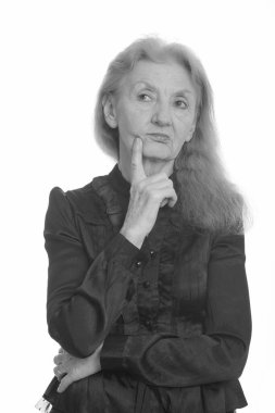 Siyah beyaz çekilen yaşlı bir kadının stüdyo portresi.
