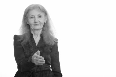 Siyah beyaz çekilen yaşlı bir kadının stüdyo portresi.